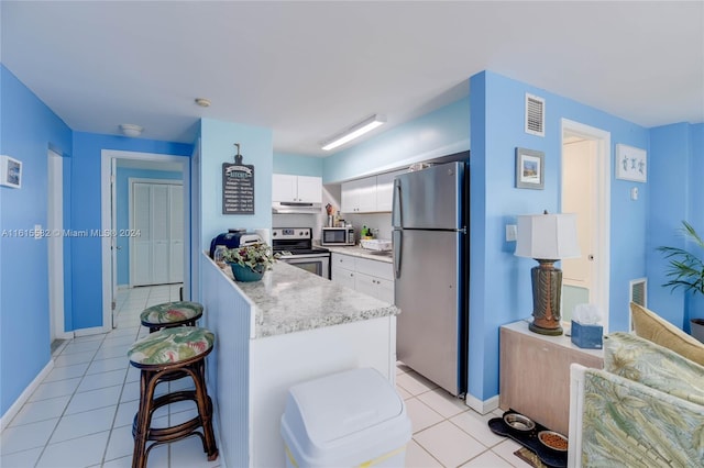 kitchen featuring white cabinetry, light tile patterned floors, a breakfast bar area, and stainless steel appliances