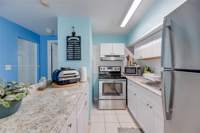 kitchen featuring light tile patterned floors, appliances with stainless steel finishes, light stone countertops, decorative backsplash, and white cabinets