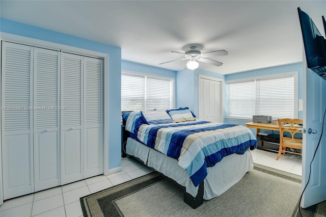 bedroom featuring ceiling fan, two closets, and light tile patterned floors