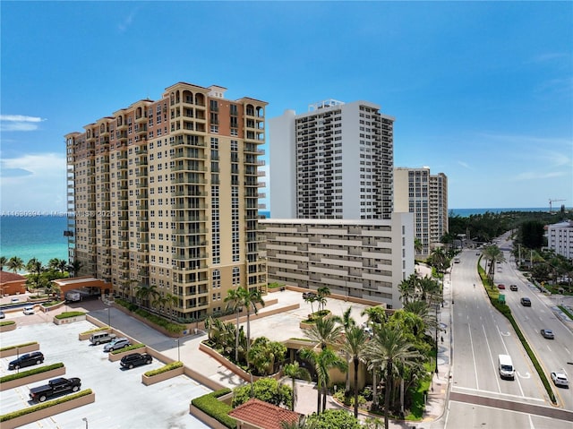 view of building exterior featuring uncovered parking, a view of city, and a water view