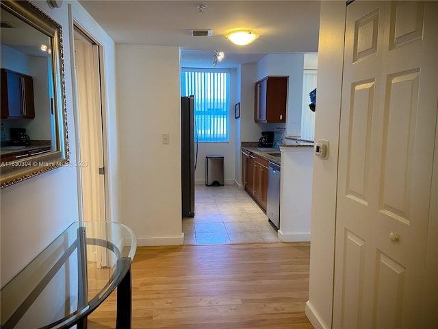 kitchen featuring refrigerator, visible vents, light wood-style flooring, stainless steel dishwasher, and baseboards