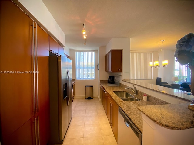 kitchen with light tile patterned floors, appliances with stainless steel finishes, a peninsula, an inviting chandelier, and a sink