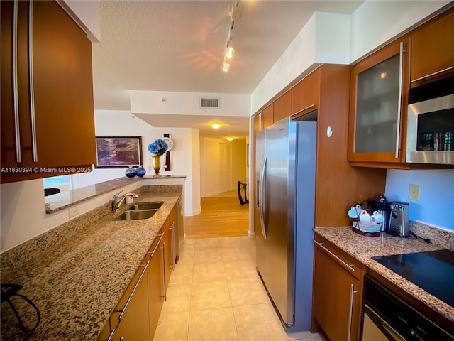 kitchen featuring light stone counters, brown cabinets, visible vents, appliances with stainless steel finishes, and a sink