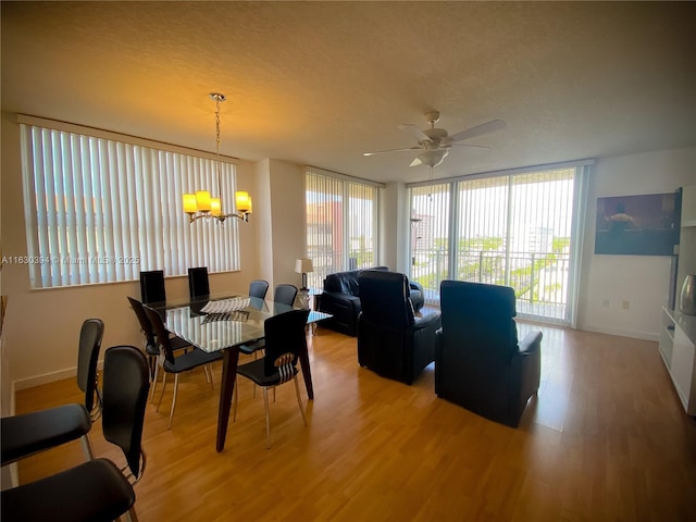 dining space featuring light wood-type flooring, floor to ceiling windows, a textured ceiling, and baseboards