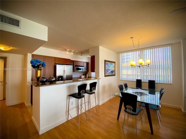 2080 S Ocean Dr Unit 701, Hallandale Beach, FL 33009 - dining area with light wood-style flooring, a chandelier, baseboards, and a textured ceiling