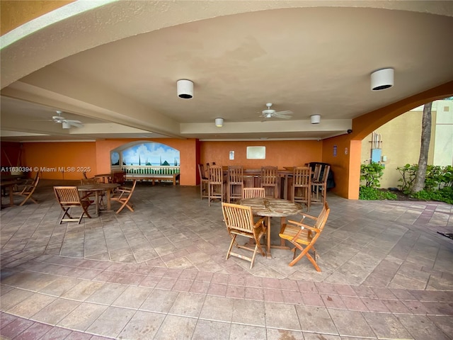 dining space with arched walkways, a bar, and a ceiling fan