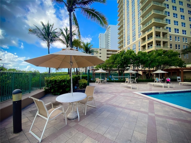 community pool with a patio area and fence