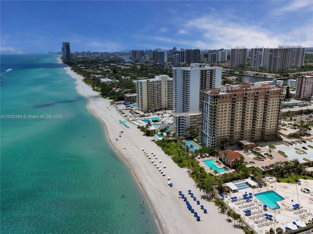 drone / aerial view featuring a water view, a beach view, and a city view