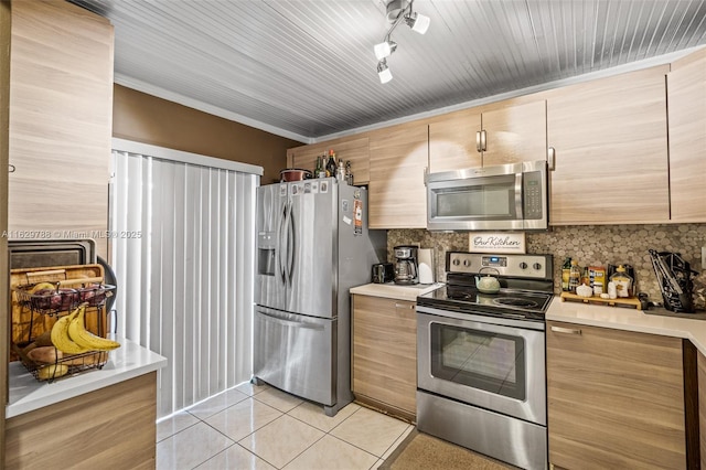 kitchen featuring stainless steel appliances, light tile patterned floors, track lighting, and backsplash