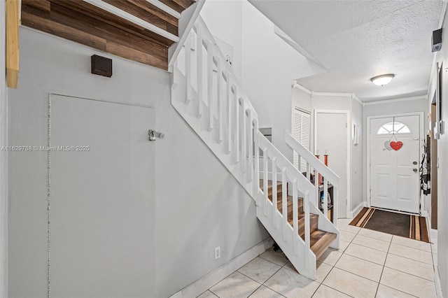 entrance foyer with a textured ceiling, light tile patterned floors, and crown molding