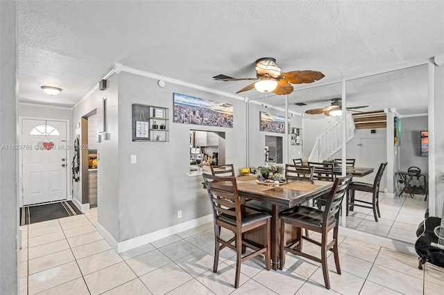 dining room featuring light tile patterned flooring, a textured ceiling, ornamental molding, and ceiling fan