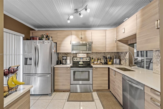 kitchen featuring sink, light tile patterned floors, light brown cabinetry, backsplash, and appliances with stainless steel finishes