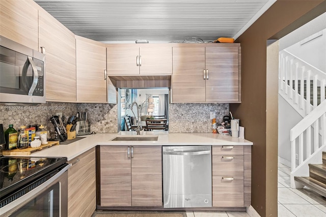 kitchen featuring sink, stainless steel appliances, light brown cabinetry, and tasteful backsplash