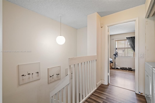 corridor featuring dark hardwood / wood-style flooring, a textured ceiling, and independent washer and dryer