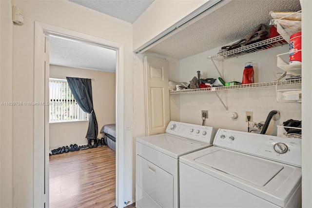 washroom featuring wood-type flooring, a textured ceiling, and independent washer and dryer