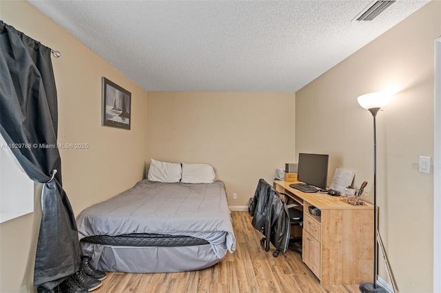 bedroom with a textured ceiling and light hardwood / wood-style flooring