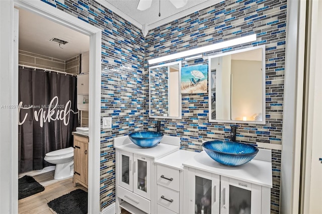 bathroom featuring toilet, hardwood / wood-style flooring, tile walls, backsplash, and vanity