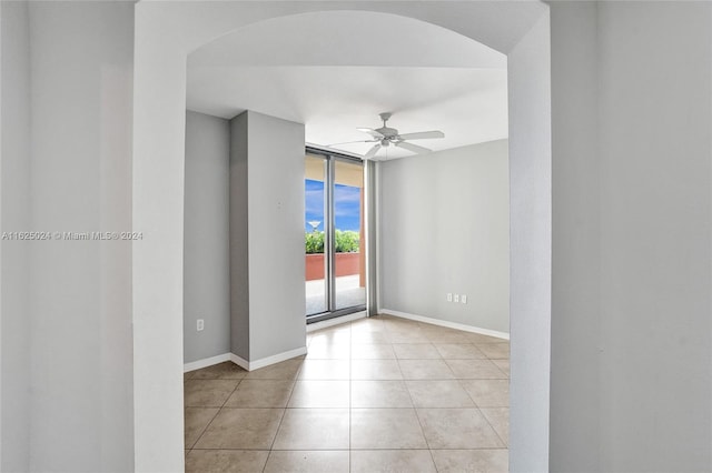 tiled empty room with ceiling fan and floor to ceiling windows