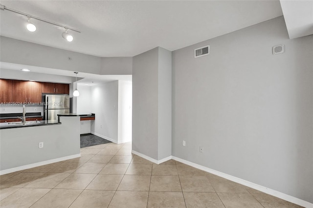 kitchen featuring decorative light fixtures, sink, light tile patterned floors, and stainless steel refrigerator