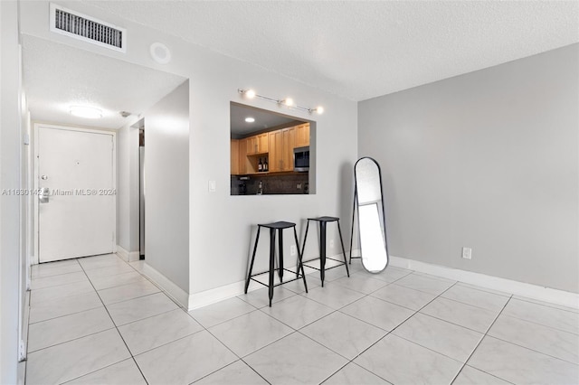 interior space featuring a textured ceiling and light tile patterned flooring