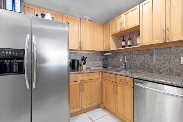 kitchen featuring light brown cabinets, backsplash, sink, light tile patterned floors, and appliances with stainless steel finishes