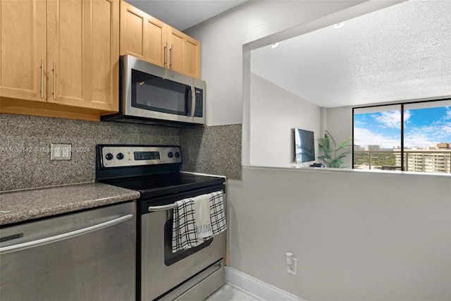 kitchen featuring backsplash, light brown cabinetry, stainless steel appliances, and a textured ceiling