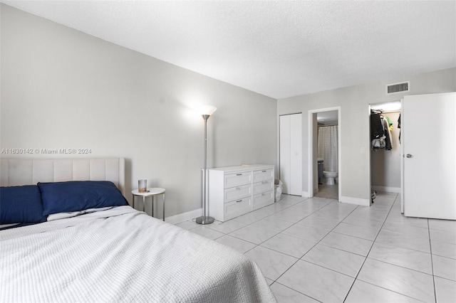 tiled bedroom with connected bathroom and a textured ceiling