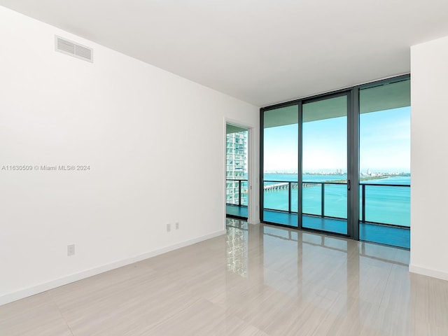 spare room featuring a water view and a wall of windows