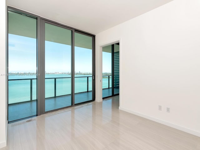 spare room with a water view and floor to ceiling windows