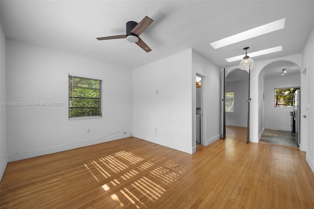 empty room with a skylight, light tile patterned flooring, and ceiling fan