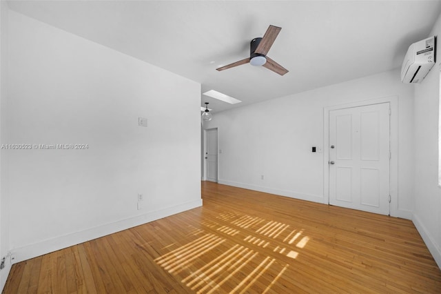 empty room featuring light hardwood / wood-style floors, a wall unit AC, and ceiling fan