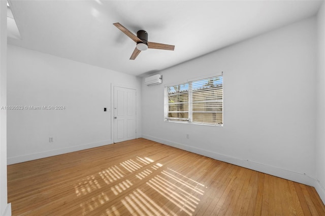 unfurnished room with a wall mounted air conditioner, light hardwood / wood-style flooring, and ceiling fan