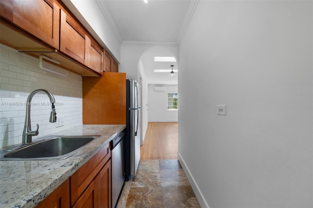 kitchen with tasteful backsplash, hardwood / wood-style flooring, sink, light stone countertops, and appliances with stainless steel finishes