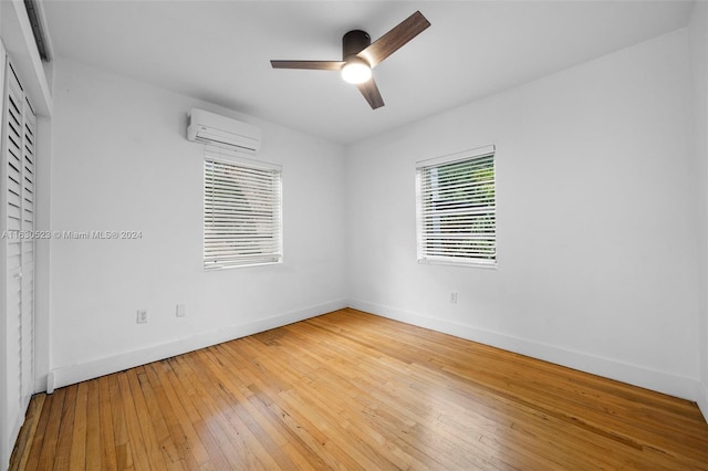 interior space with light hardwood / wood-style flooring, a wall mounted air conditioner, and ceiling fan