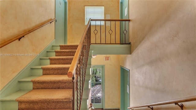 staircase featuring a high ceiling and a wealth of natural light