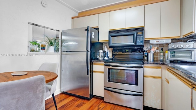 kitchen with tasteful backsplash, light hardwood / wood-style floors, white cabinets, and appliances with stainless steel finishes