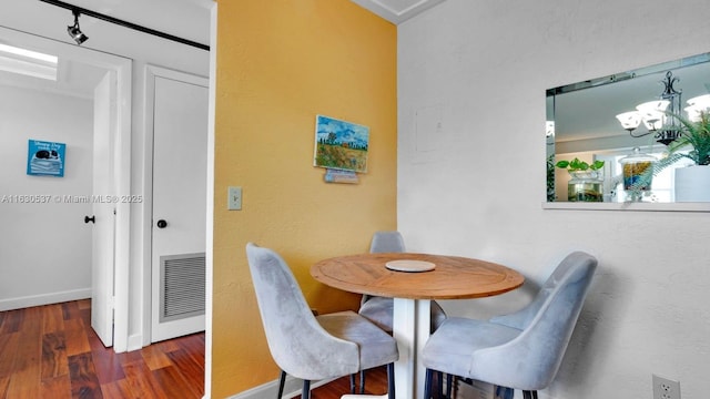 dining room with dark wood-type flooring and a chandelier