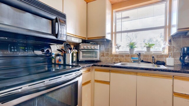 kitchen with black appliances, backsplash, white cabinetry, and sink