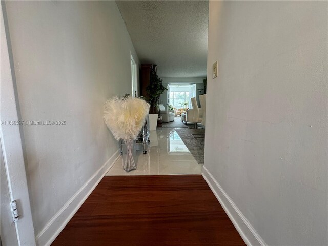 hallway with a textured ceiling and hardwood / wood-style flooring