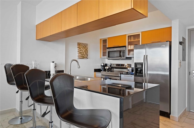 kitchen with light tile patterned floors, sink, stainless steel appliances, and a breakfast bar