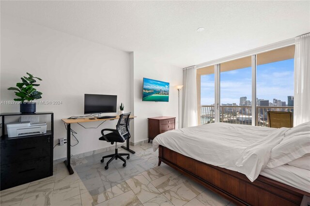 bedroom with a wall of windows, light tile patterned floors, and access to exterior