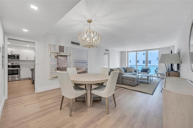 dining area with a notable chandelier, light hardwood / wood-style flooring, and expansive windows