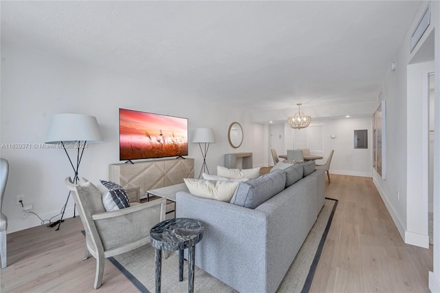 living room with a chandelier, light hardwood / wood-style flooring, and electric panel