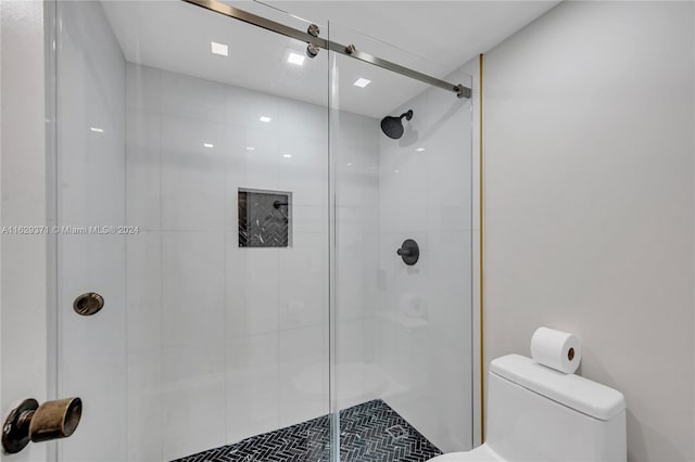 bathroom featuring a shower with shower door and toilet