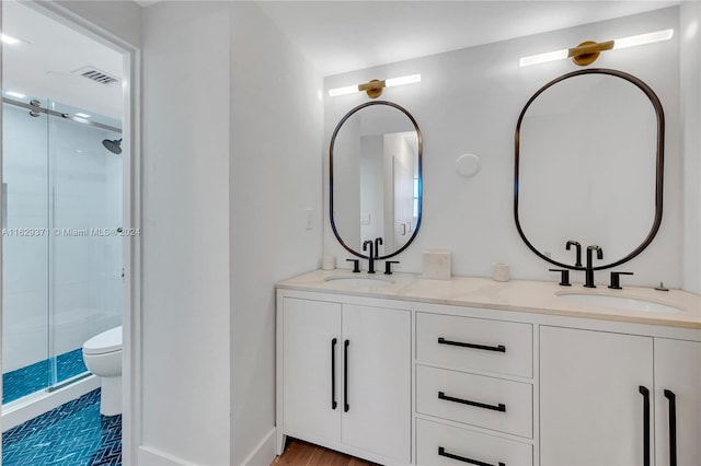 bathroom with dual vanity, a shower with door, and toilet