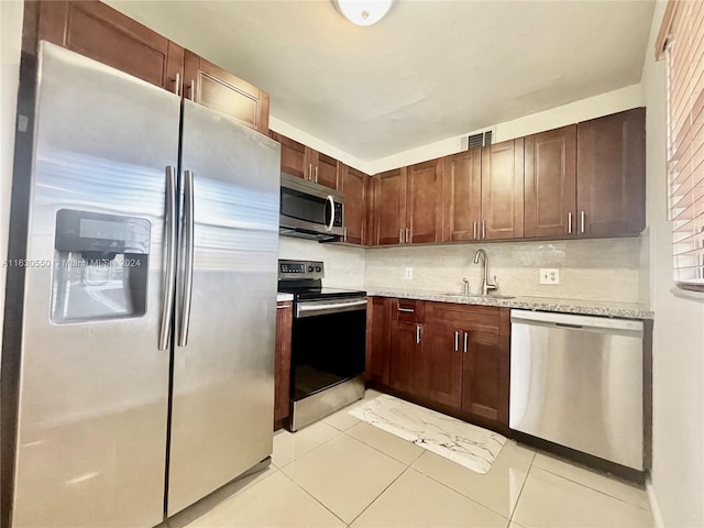 kitchen featuring sink, stainless steel appliances, backsplash, and light tile patterned floors