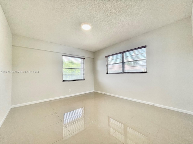 tiled empty room with a textured ceiling