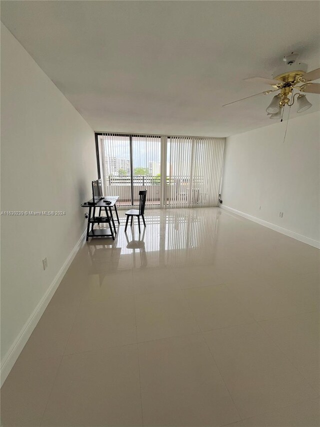 tiled spare room with expansive windows and ceiling fan