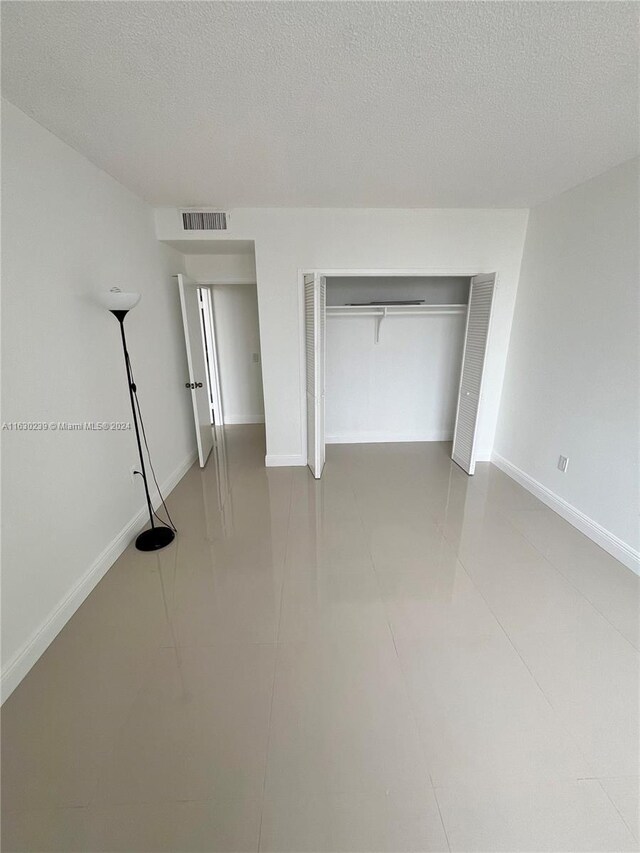 unfurnished bedroom with tile patterned flooring, a closet, and a textured ceiling