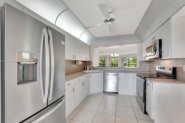 kitchen with pendant lighting, sink, white cabinets, and appliances with stainless steel finishes